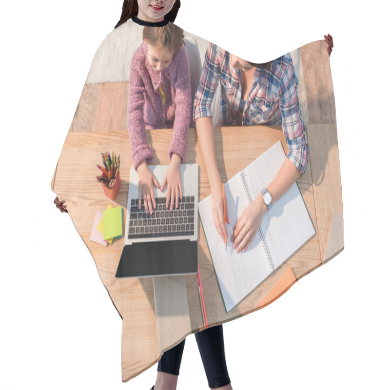 Personality  Top View Of Mother Sitting Near Daughter Typing On Laptop At Desk With Stationery At Home Hair Cutting Cape