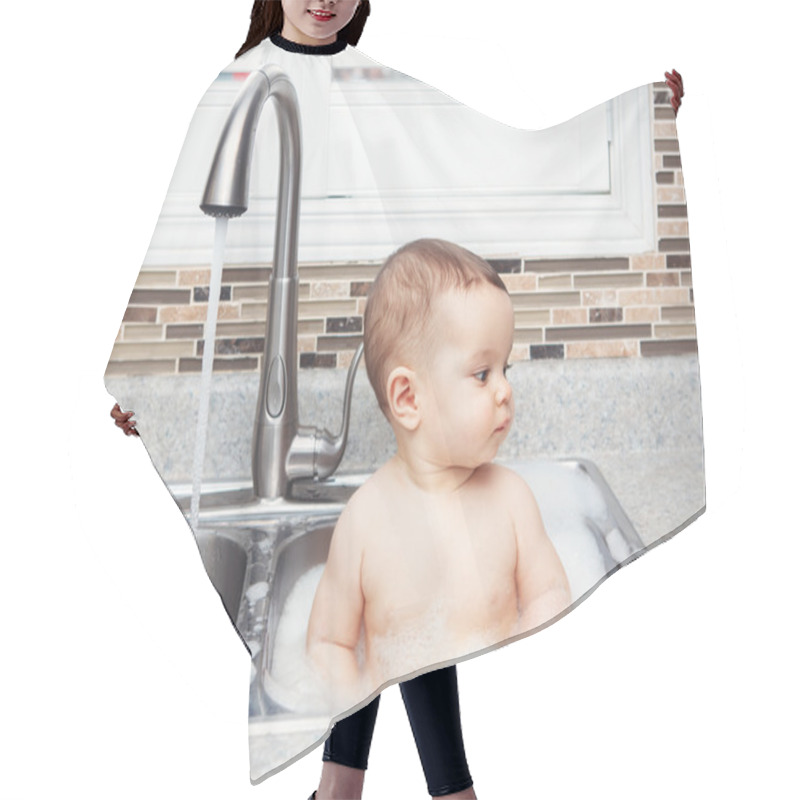 Personality  Portrait Of Cute Caucasian Funny Baby Girl Boy With Dark Black Eyes Sitting In Big Kitchen Sink With Water And Foam  Near Window Looking Away, Lifestyle Everyday Concept Hair Cutting Cape