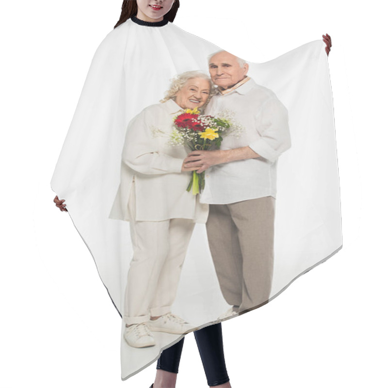 Personality  Happy Elderly Couple Hugging, Holding Bouquet Of Flowers And Looking At Camera On White Hair Cutting Cape