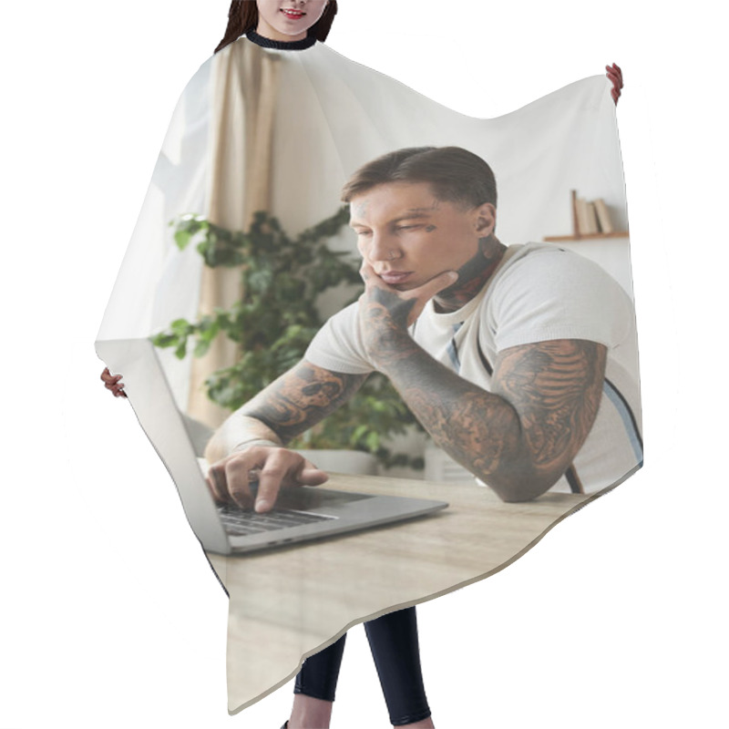 Personality  Handsome Young Man Focused On Laptop, Showcasing Tattoos In Stylish Home Environment. Hair Cutting Cape