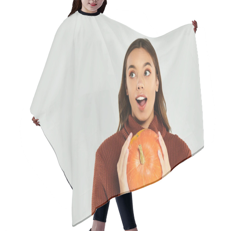 Personality  A Surprised Young Woman Holds A Bright Orange Pumpkin, Embracing The Halloween Spirit. Hair Cutting Cape