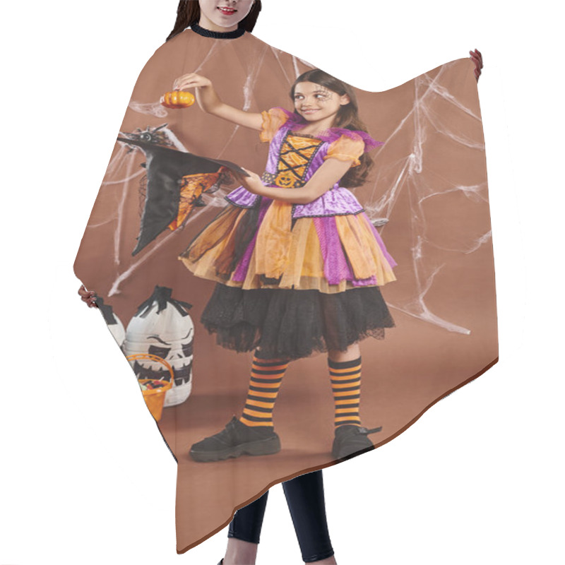 Personality  Happy Child In Halloween Witch Costume Holding Pumpkin Near Pointed Hat On Brown Background Hair Cutting Cape