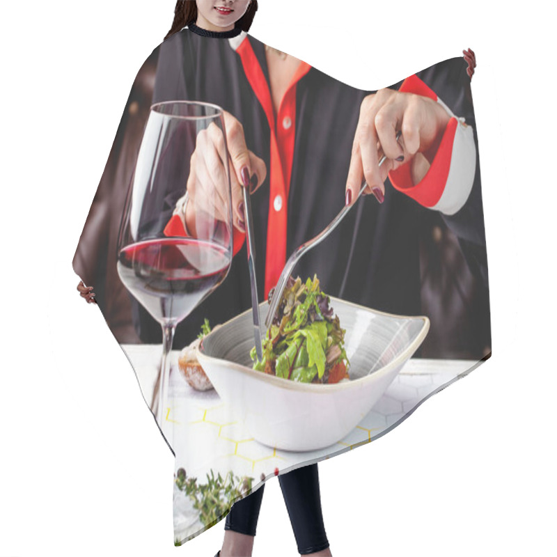 Personality  The Girl In The Restaurant Has An Evening Dinner, A Vegetarian Salad. Knife And Fork In Hands. A Glass Of Red Wine Is On The Table Hair Cutting Cape