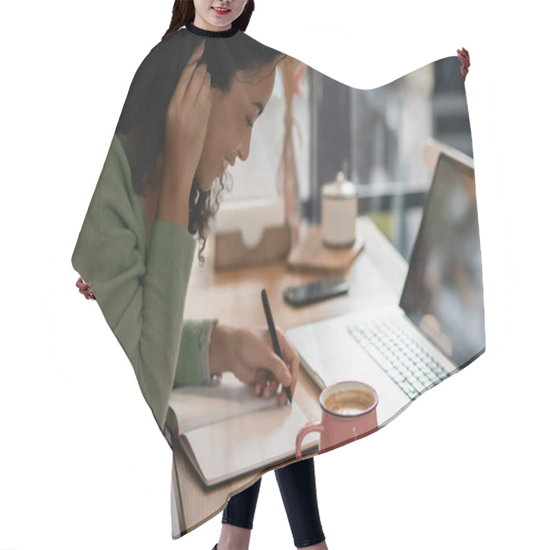 Personality  Happy African American Woman Fixing Hair While Writing In Notebook Near Laptop And Cup Of Coffee In Cafe Hair Cutting Cape