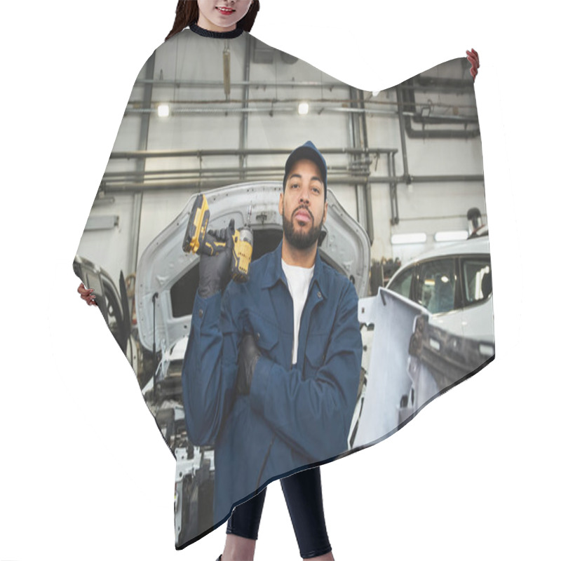 Personality  Young Man In Blue Work Uniform Stands Proudly With Tools In A Bustling Mechanic Workshop. Hair Cutting Cape