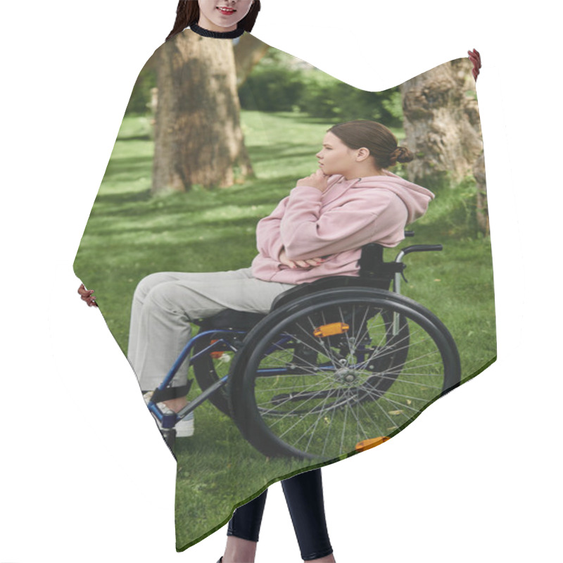 Personality  A Young Woman In A Pink Hoodie Sits In A Wheelchair In A Grassy Park. Hair Cutting Cape