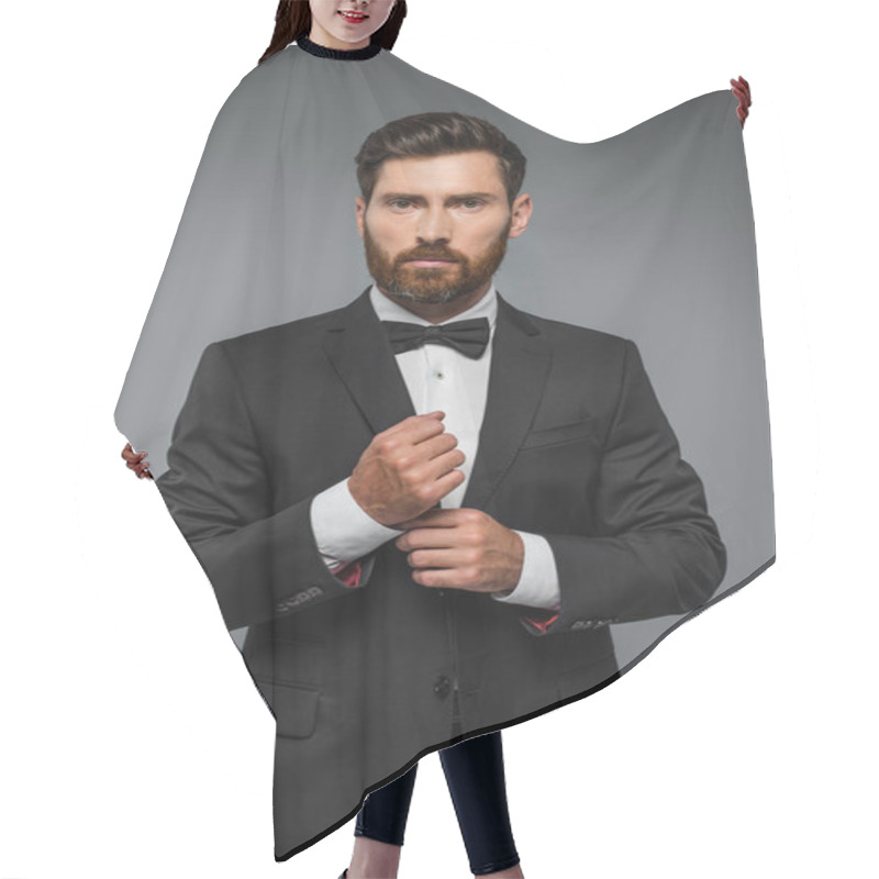 Personality  Bearded Man In Black Tuxedo With Bow Tie Adjusting Sleeve On Shirt Isolated On Grey Hair Cutting Cape