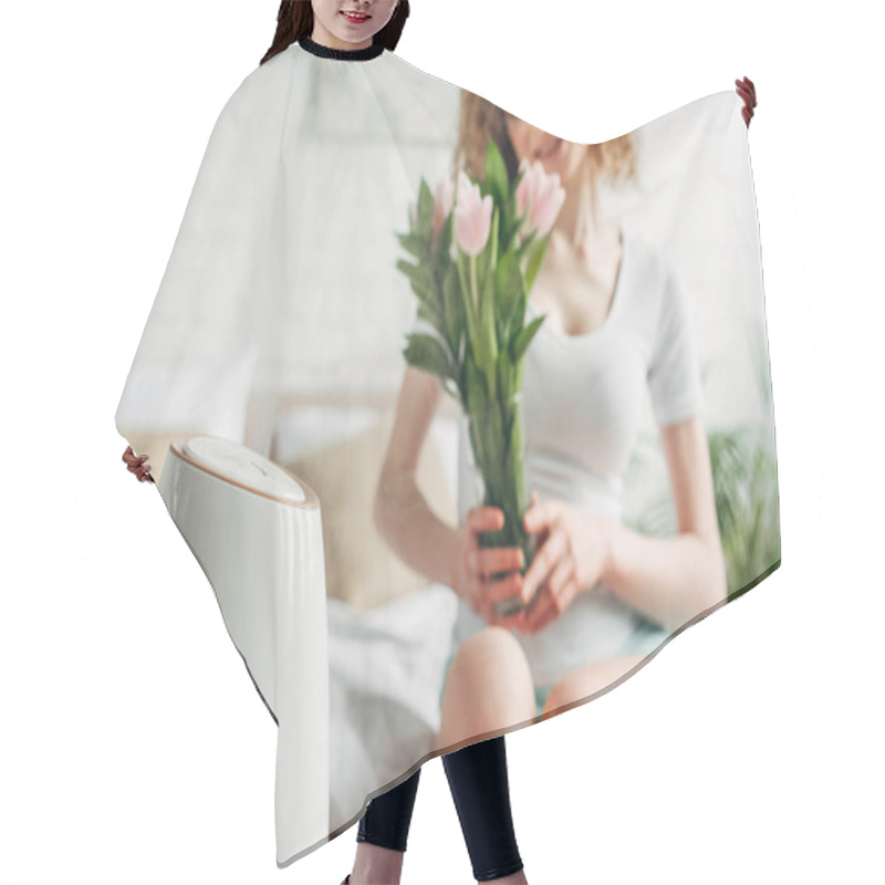 Personality  Selective Focus Of Smiling Girl Holding Tulip Flowers While Sitting In Bedroom With Air Purifier  Hair Cutting Cape