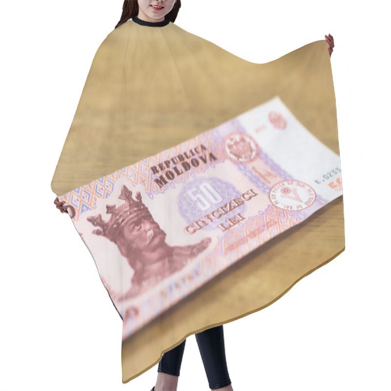 Personality  A Fifty Moldovan Leu Banknote Rests On A Light Brown Wooden Surface.  The Bill Features A Portrait Of A Crowned Man And Intricate Design Elements.  The Colors Are Predominantly Pink, Purple, And Brown. Hair Cutting Cape