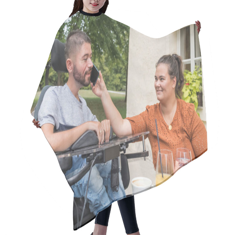 Personality  Woman Helping Her Husband With A Disability To Use A Mobile Phone While They Enjoy Leisure Time At The Cafe Outdoors. Hair Cutting Cape