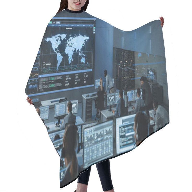 Personality  Shot Of Officers In A Surveillance Control Center With Police Global Map Tracking On A Big Digital Screen. Monitoring Room Employees Sit In Front Of Computer Displays And Analyze Big Data. Hair Cutting Cape