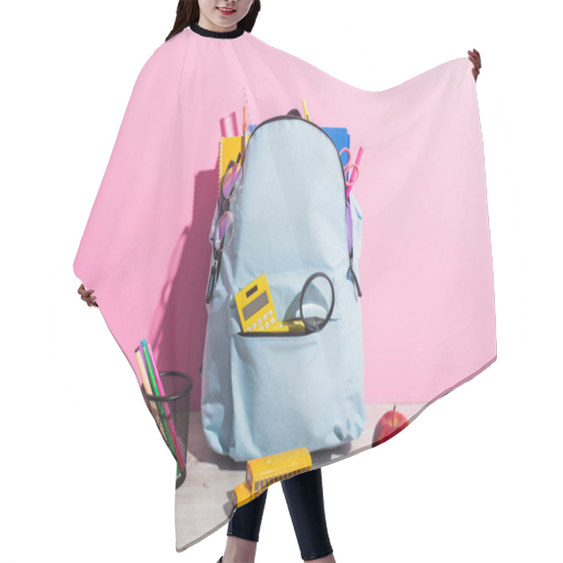 Personality  Blue Backpack Packed With School Stationery Near School Bus Model, Books, Ripe Apple And Pen Holder On Pink Hair Cutting Cape