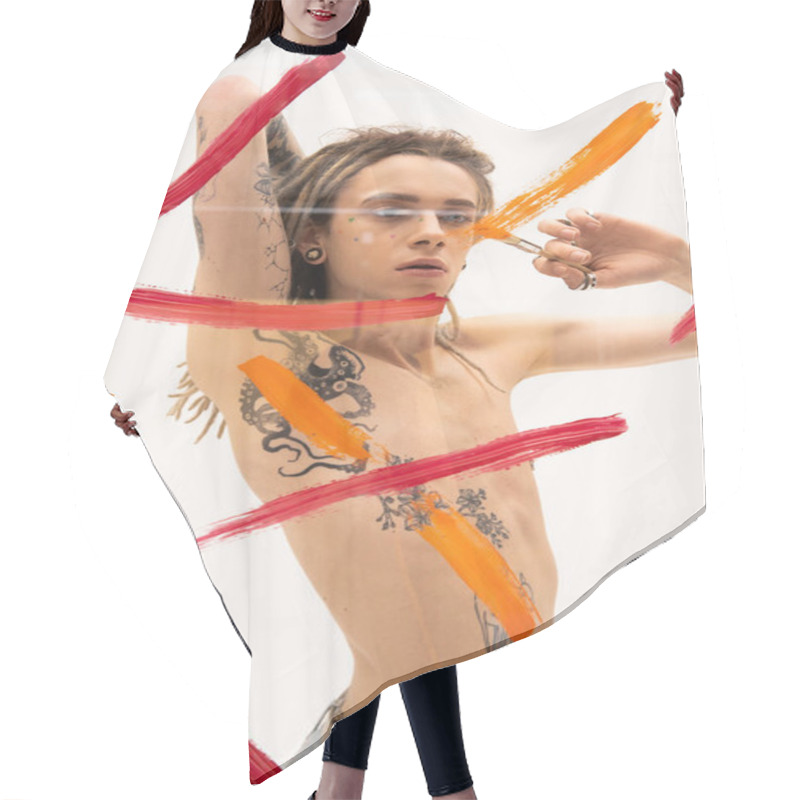 Personality  Shirtless Nonbinary Model With Tattooed Body Painting On Glass Surface While Standing On White Background  Hair Cutting Cape