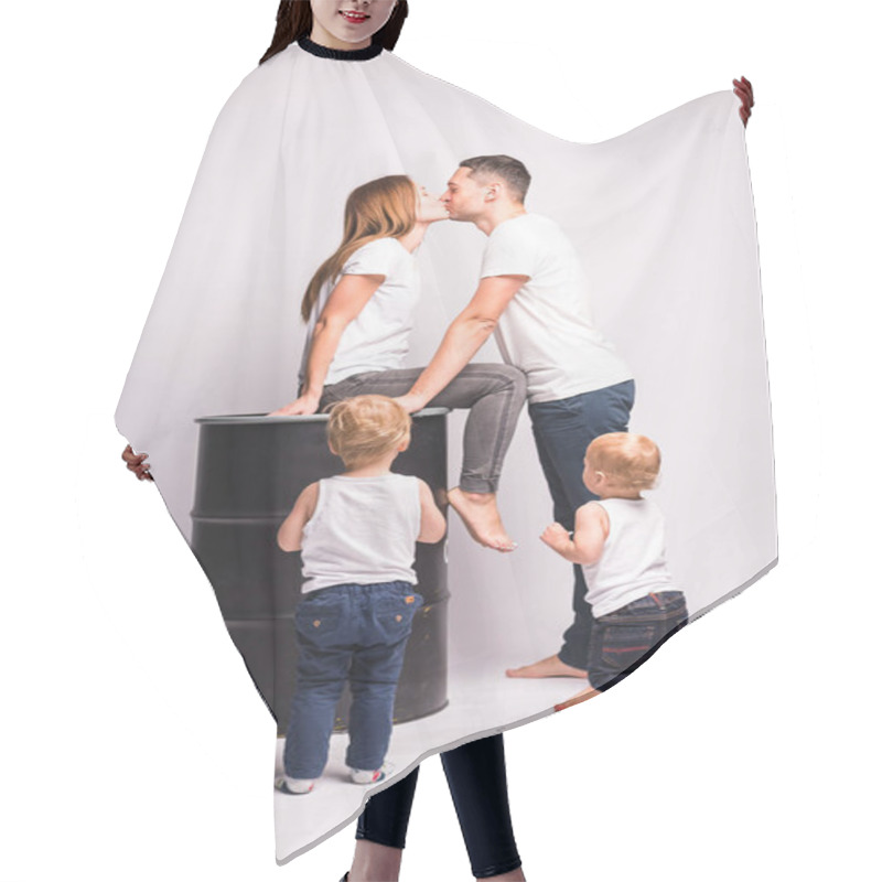 Personality  Mom Sits On A Barrel And Kisses Dad, The Children Have Fun Next To Her. Happy European Family Spend Time Together, The Family Is Happy. Mom, Dad, Son, Two Sons, Smiling And Messing Around, Crazy Fun. Spending Time With Family.white T-shirts And Jeans Hair Cutting Cape