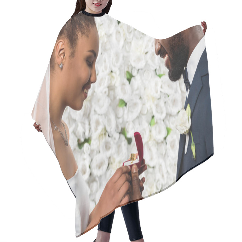 Personality  Cheerful African American Bride Looking At Box With Ring Near Happy Bridegroom And Flowers  Hair Cutting Cape