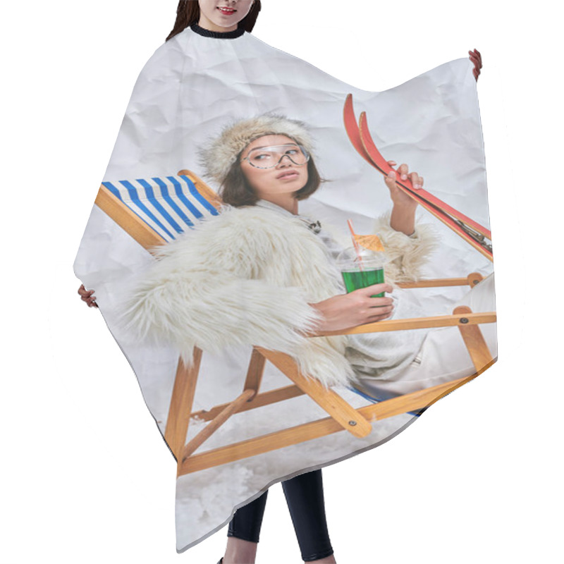 Personality  Asian Woman In Eyeglasses And Winter Wear Relaxing In Deck Chair With Cocktail And Skis In Studio Hair Cutting Cape