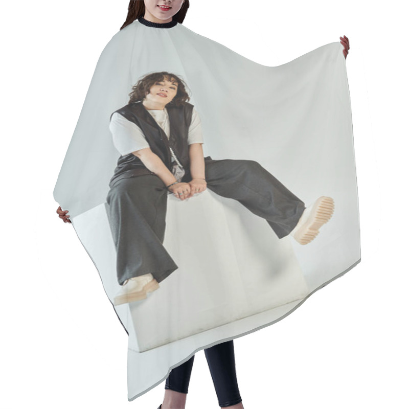 Personality  Confident Woman With Dark Hair In Black Pants And White Shirt, Seated On White Cube Hair Cutting Cape