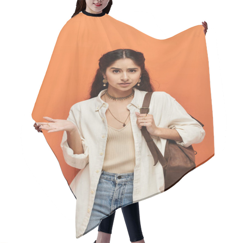 Personality  Stylish Indian Woman In Jeans And White Shirt Stands Confidently Against Vibrant Orange Backdrop. Hair Cutting Cape