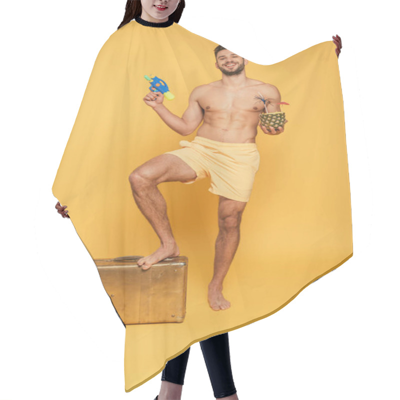 Personality  Happy Shirtless Man Holding Water Gun Cocktail In Pineapple While Stepping On Vintage Suitcase On Yellow Background Hair Cutting Cape