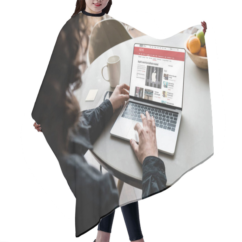 Personality  KYIV, UKRAINE - APRIL 25, 2020: Back View Of Freelancer Using Laptop With BBC News And Apple Logo On Screen Near Coffee Cup, Sticky Notes And Fruits Hair Cutting Cape