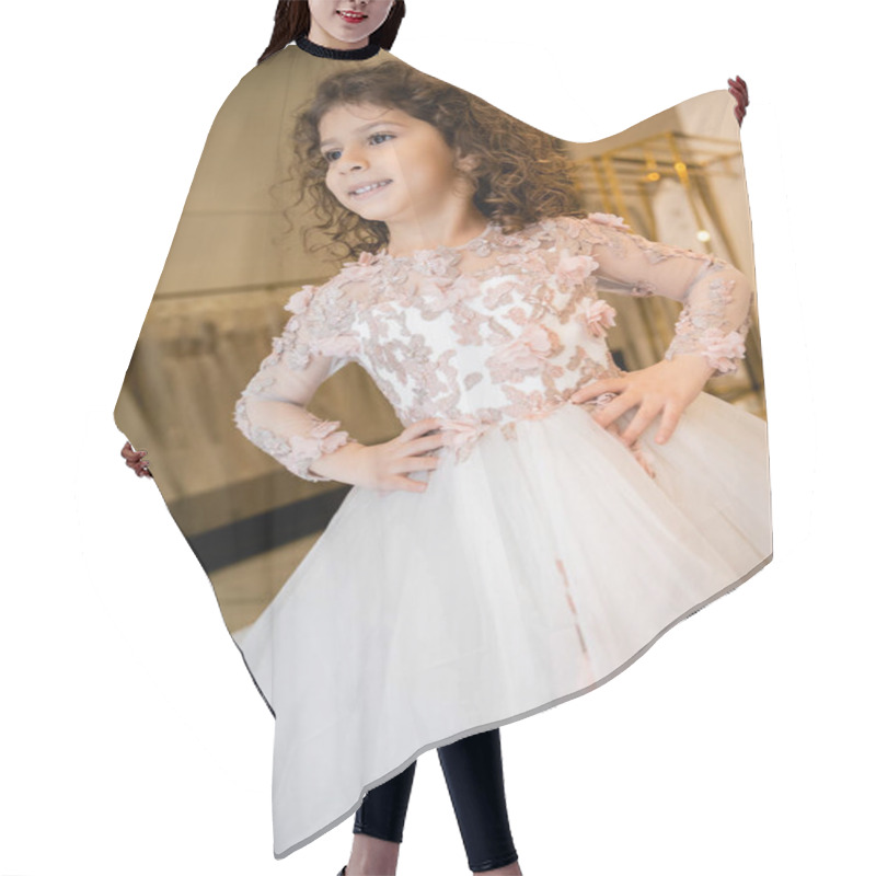 Personality  Joyous Middle Eastern Kid In Floral Dress With Tulle Skirt Standing With Hands On Hips And Looking Away In Bridal Boutique, Preparation For Wedding, Blurred Background, Low Angle, Flower Girl Hair Cutting Cape