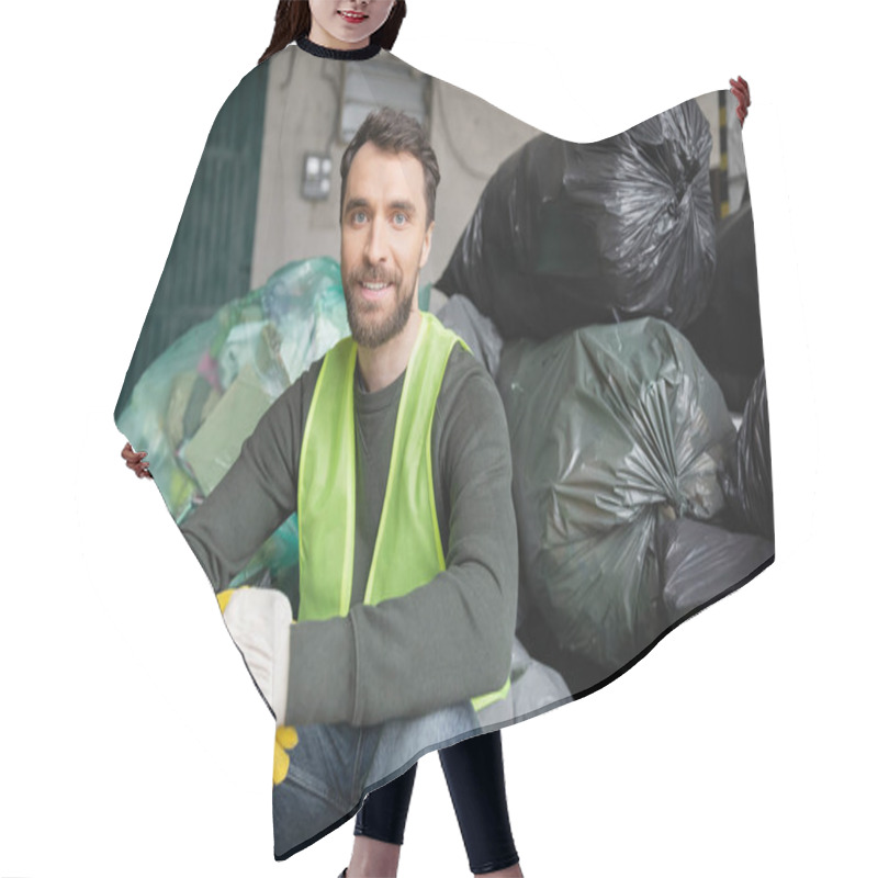 Personality  Smiling And Bearded Worker In Safety Vest And Gloves Looking At Camera While Sitting On Plastic Bags With Trash In Blurred Garbage Sorting Center, Recycling Concept Hair Cutting Cape