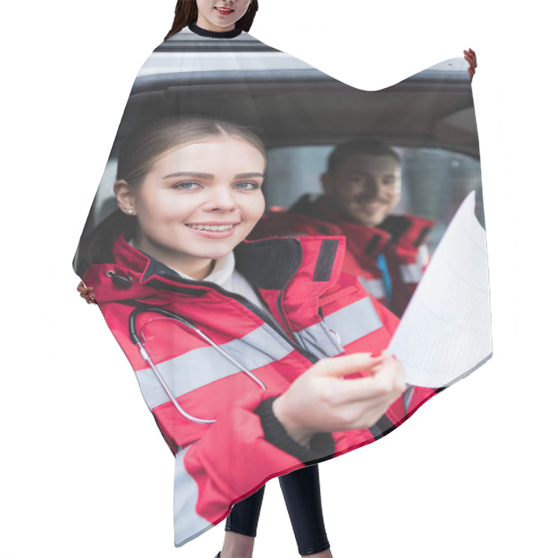 Personality  Smiling Young Female Paramedic Holding Clipboard And Looking At Camera Hair Cutting Cape