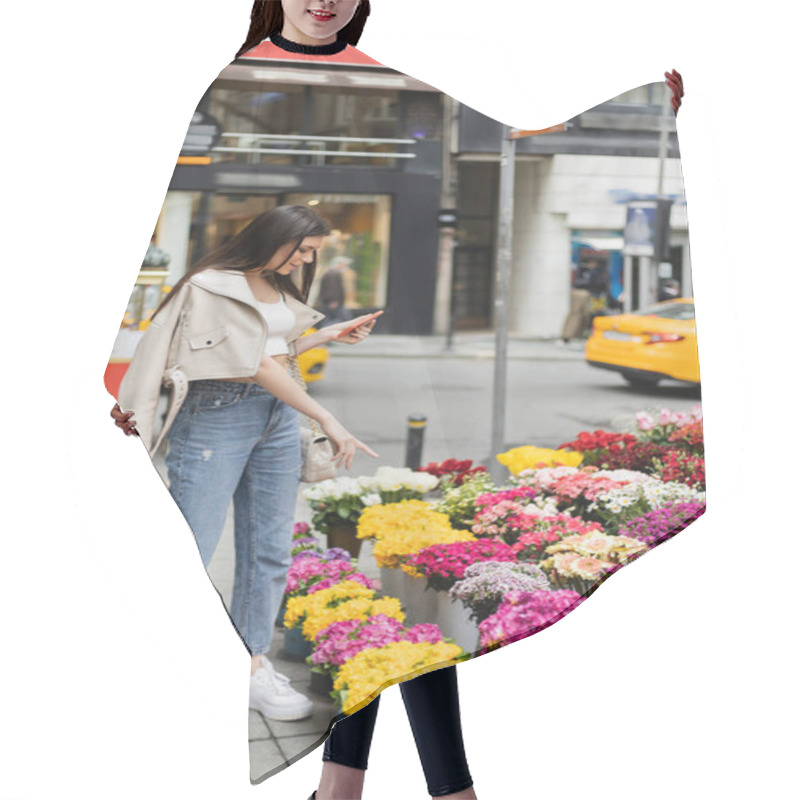 Personality  Brunette Woman With Long Hair Standing In Beige Leather Jacket And Denim Jeans While Holding Smartphone And Pointing At Bouquets Of Flowers Next To Blurred Car On Street In Istanbul, Vendor Hair Cutting Cape