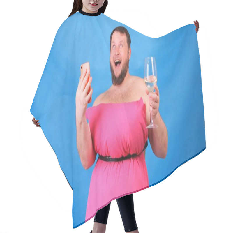 Personality  Funny Bearded Guy In A Pink Dress Made Of Pillows With A Glass Of Wine Makes Selfie On A Blue Background. Crazy Quarantine. Funny House Cleaning. Fashion 2020. Put On A Pillow. Challenge 2020 Due To Hair Cutting Cape