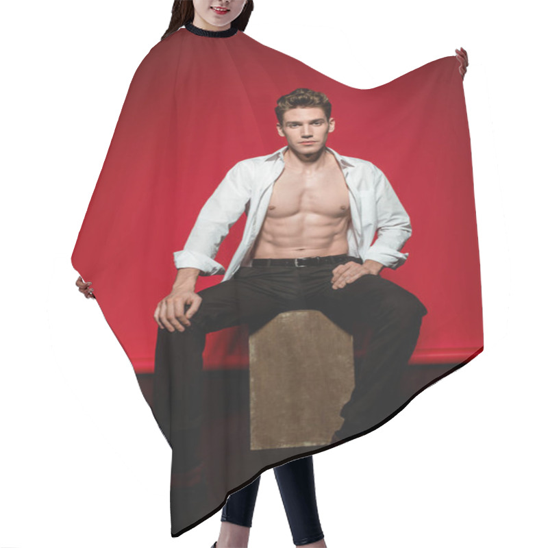 Personality  Sexy Young Elegant Man In Unbuttoned Shirt With Muscular Bare Torso Posing On Box On Red Background Hair Cutting Cape