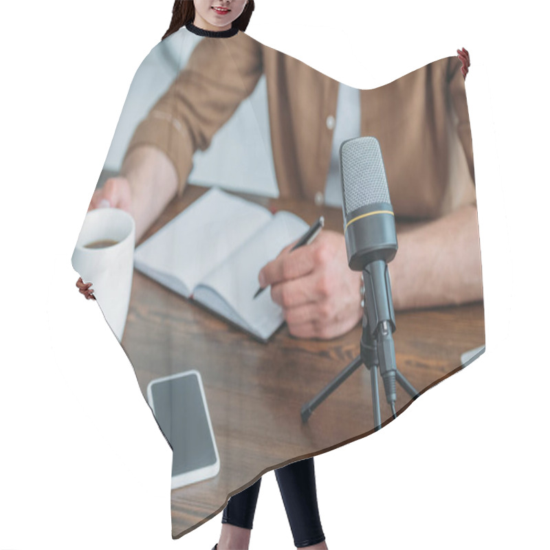 Personality  Cropped View Of Radio Host Writing In Notebook While Sitting At Desk Near Smartphone With Blank Screen And Cup Of Coffee Hair Cutting Cape