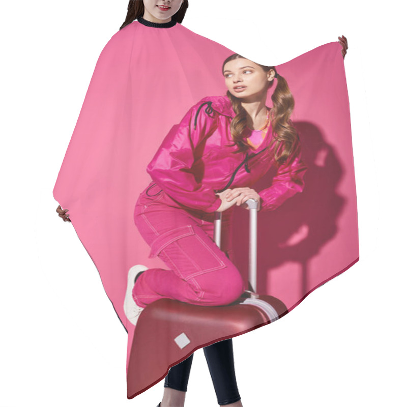 Personality  A Stylish Young Woman In Her 20s Sitting On Top Of A Suitcase In A Studio With A Pink Background. Hair Cutting Cape