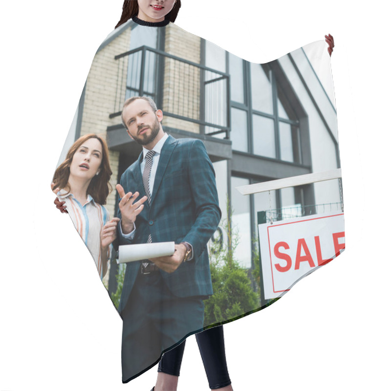 Personality  Handsome Broker Holding Clipboard And Gesturing Near Beautiful Woman And Board With Sale Letters  Hair Cutting Cape