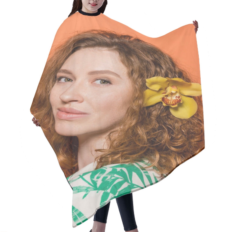 Personality  Portrait Of Young Redhead Woman With Orchid Flower In Hair And Natural Makeup Looking At Camera While Standing On Orange Background, Summer Casual And Fashion Concept, Youth Culture Hair Cutting Cape