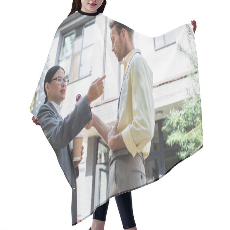 Personality  Low Angle View Of Reporter Holding Microphone Near Asian Businesswoman Holding Paper Cup And Pointing Away While Giving Interview  Hair Cutting Cape