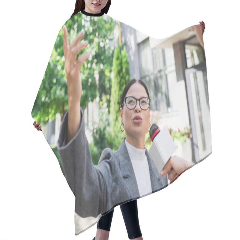 Personality  Reporter Holding Microphone Near Asian Businesswoman With Paper Cup And Pointing Away While Giving Interview  Hair Cutting Cape