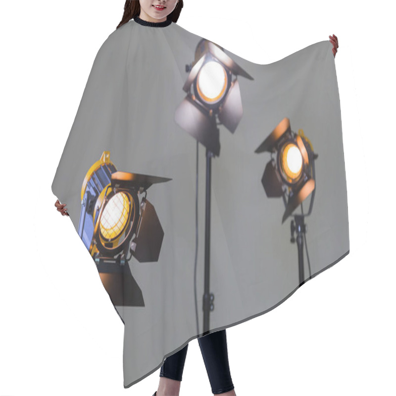 Personality  Three Halogen Spotlights With Fresnel Lenses On A Grey Background. Photographing And Filming In The Interior. Lighting Equipment For Movie Production Hair Cutting Cape