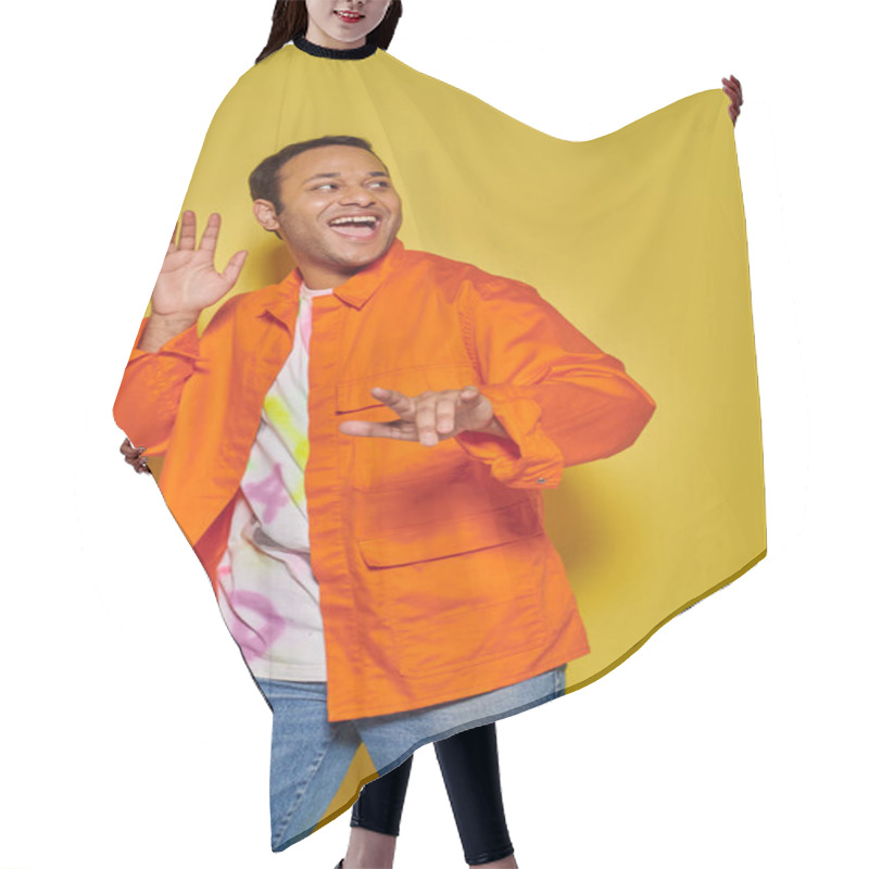 Personality  Portrait Of Astonished Indian Man In Orange Jacket And Diy T-shirt Gesturing On Yellow Backdrop Hair Cutting Cape