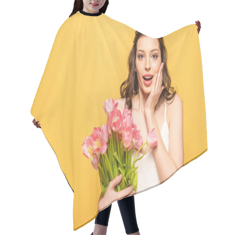 Personality  Shocked Young Woman Holding Bouquet Of Pink Tulips And Touching Face While Looking At Camera Isolated On Yellow Hair Cutting Cape