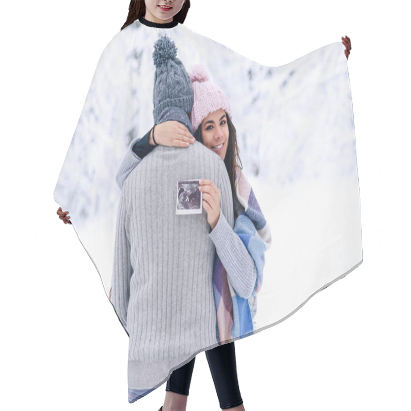 Personality  Beautiful Pregnant Woman In Warm Pink Hat Hugs Gently Her Husband And Holds Ultrasonic Pregnant Picture In Her Hand. Family Love And Care Concept. Hair Cutting Cape