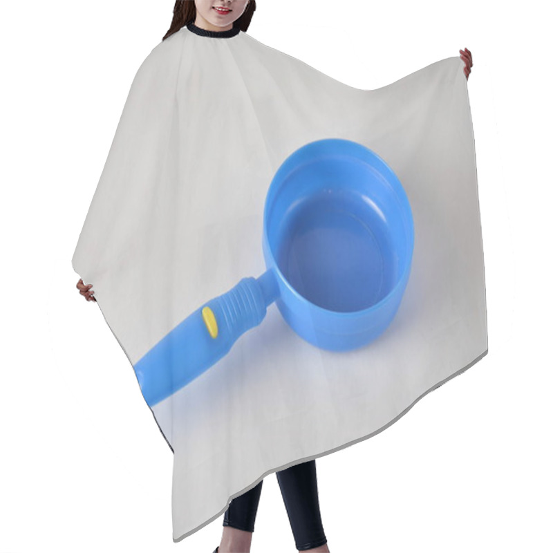 Personality  Blue Plastic Toy Frying Pan With Yellow Accent On The Handle, Against A Plain Background. Hair Cutting Cape