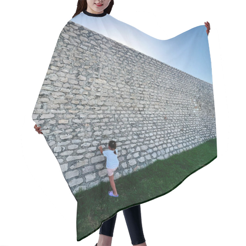 Personality  A Young Girl In Casual Attire Exploring A Large Stone Wall On A Bright Sunny Day, Showcasing Curiosity And Adventure. The Lush Green Grass Adds A Vibrant Contrast To The Scene. Nin, Croatia. Hair Cutting Cape