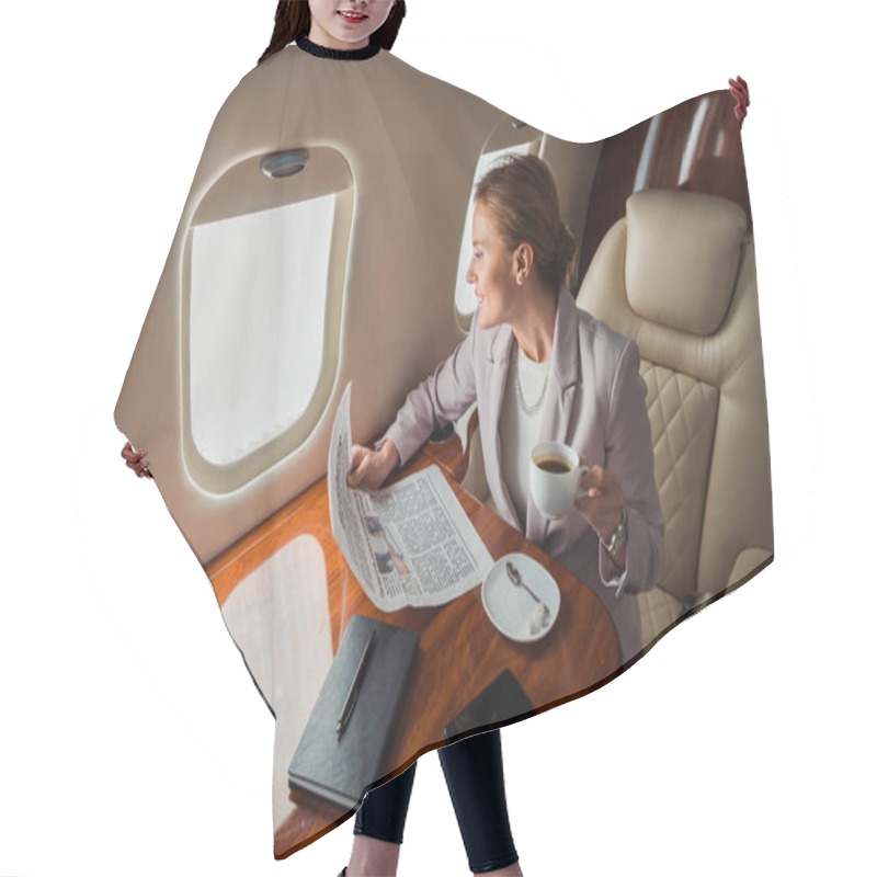 Personality  Cheerful Businesswoman Holding Cup And Business Newspaper Near Smartphone With Blank Screen In Private Plane  Hair Cutting Cape