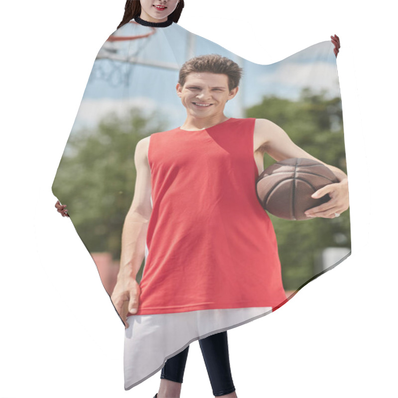 Personality  A Young Man In A Red Shirt Skillfully Holds A Basketball On A Sunny Summer Day Outdoors. Hair Cutting Cape