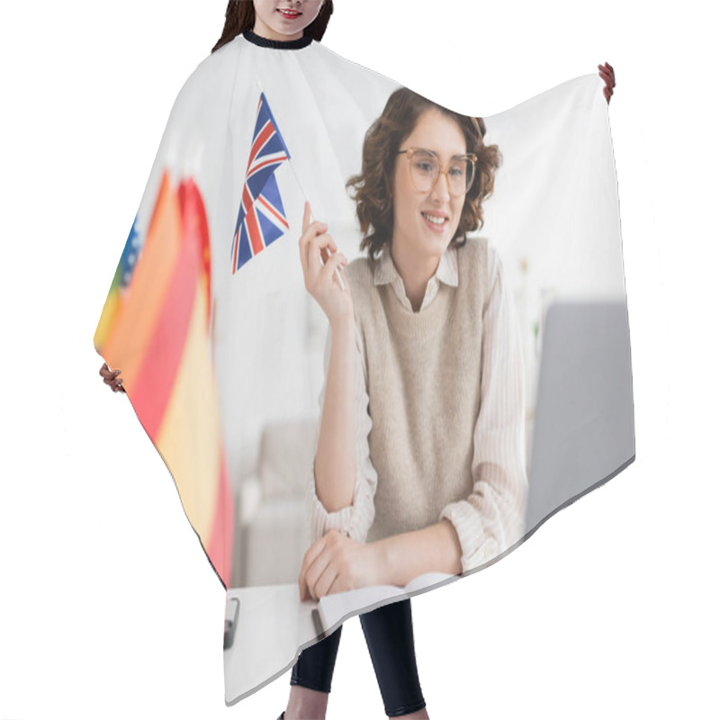 Personality  Smiling Language Teacher In Eyeglasses Holding Flag Of United Kingdom Near Notebook And Blurred Laptop  Hair Cutting Cape