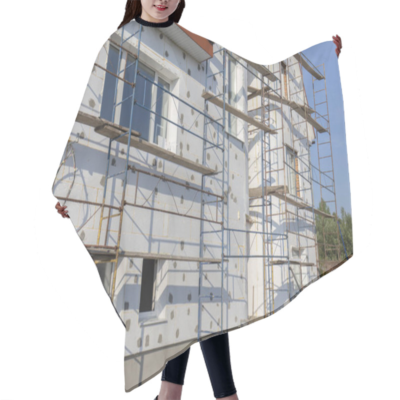 Personality  The Process Of Building Wall Insulation Using Polystyrene In The Open Air. Scaffold On House, Renovation. House For Renovation With The Scaffolding For Workers On Building, Close Up Hair Cutting Cape