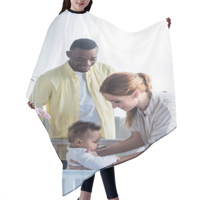 Personality  Smiling Woman Holding Infant Daughter Near Crib And African American Husband Hair Cutting Cape