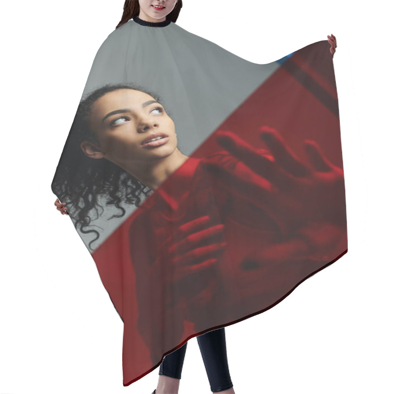 Personality  A Young African American Woman With Curly Hair Poses In A Studio, With Red Light Illuminating Her From Behind. Hair Cutting Cape