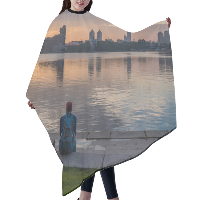 Personality  YEKATERINBURG, RUSSIA - 1 JULY, 2017: A Man Is Sitting On The Embankment And Looking At The Sunset, The City Pond, Iset/ Hair Cutting Cape