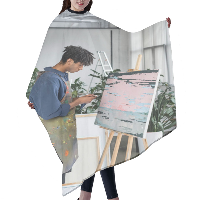 Personality  Side View Of African American Artist In Apron Holding Paintbrush And Paint Near Drawing In Studio  Hair Cutting Cape